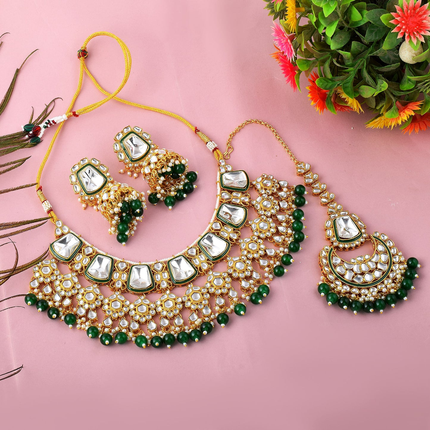 Green imitation jewellery necklace set with earrings and maang tikka flat lay