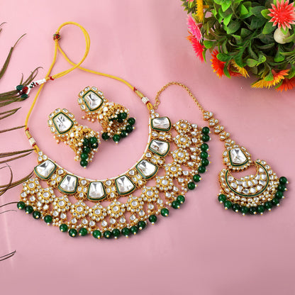 Green imitation jewellery necklace set with earrings and maang tikka flat lay