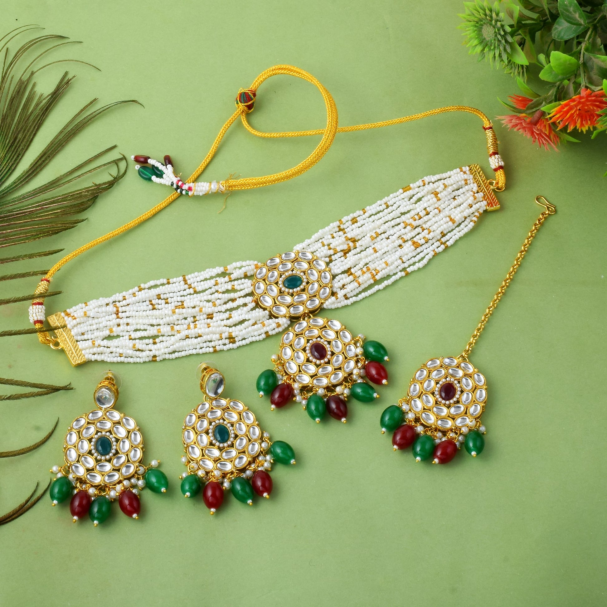 Multi color imitation jewellery necklace set with earrings and maang tikka flat lay